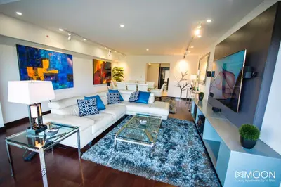 a living room with a white couch and blue pillows at Moon Luxury Apartments in Lima