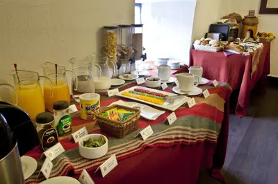 a table with a red table cloth with food and drinks at Tierra Viva Cusco Saphi Hotel in Cusco