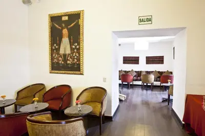 a waiting room with tables and chairs and a painting on the wall at Tierra Viva Cusco Saphi Hotel in Cusco