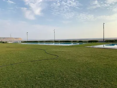a grassy field with a pool of water in the distance at La Casa del Jota in Asia