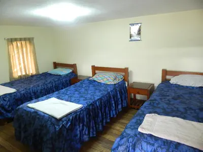 a room with three beds with blue sheets at Wichana Wasi in Cusco