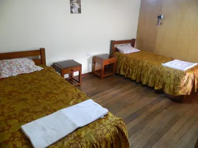 a hotel room with two beds and two tables at Wichana Wasi in Cusco