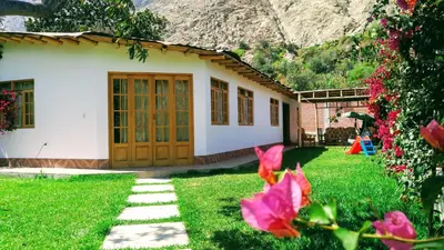 a house with a green yard with pink flowers at Casa de Campo Belén - Lunahuaná in Lunahuaná