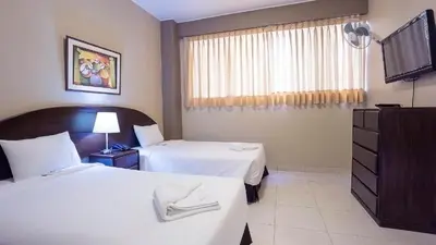 a hotel room with two beds and a flat screen tv at Suites Larco 656 Miraflores Lima in Lima