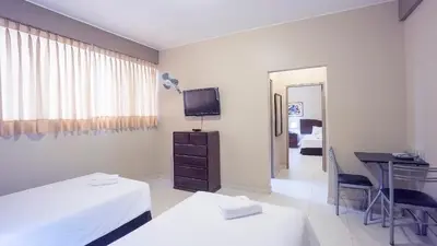a bedroom with two beds and a desk and a television at Suites Larco 656 Miraflores Lima in Lima
