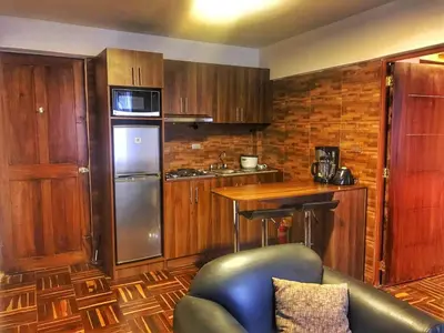 a kitchen with wooden cabinets and a couch in a room at Excelente ubicación en el Centro Cusco Inlove in Cusco