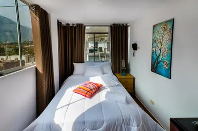 a bedroom with a white bed with a window at El Encanto in Lunahuaná