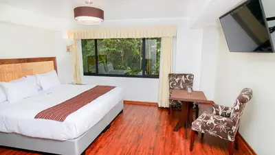 a bedroom with a bed and a desk and a window at Golden Sunrise Machupicchu in Machu Picchu