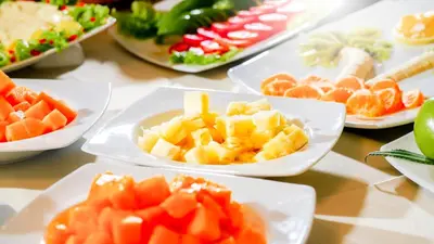 a table topped with white plates of fruit and vegetables at Golden Sunrise Machupicchu in Machu Picchu