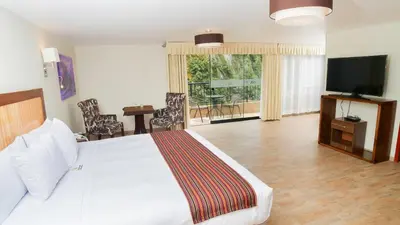 a bedroom with a large white bed and a television at Golden Sunrise Machupicchu in Machu Picchu