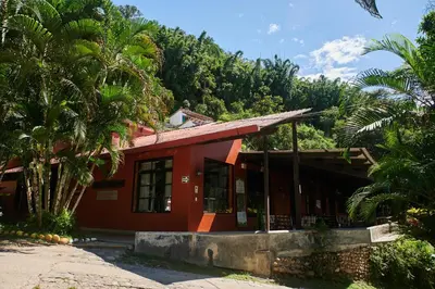 a red building with palm trees in front of it at Fundo San Jose Parque Ecológico & Lodge Hotel Asociado Casa Andina in La Merced