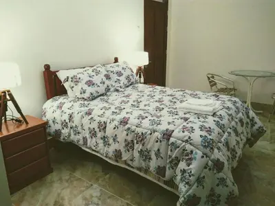 a bedroom with a bed with a floral comforter and a table at Hotel Elizabeth Hoss in Sayán