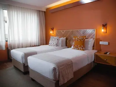 two beds in a hotel room with orange walls at qema Lima in Lima