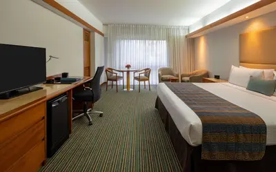 a hotel room with a bed and a desk with a television at Sonesta Hotel El Olivar in Lima