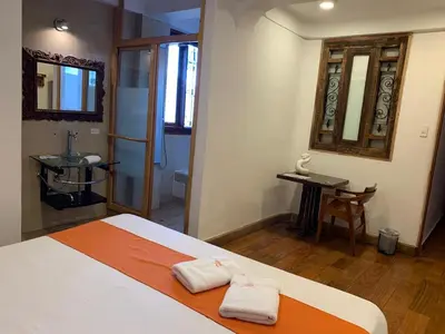 a bedroom with a bed and a table and a mirror at Waman Qorikancha in Cusco