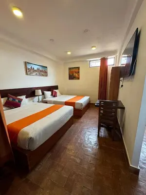 a hotel room with two beds and a desk at Waman Qorikancha in Cusco