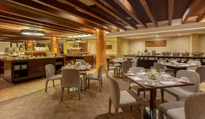 a restaurant with tables and chairs and a kitchen at Sonesta Hotel Cusco in Cusco