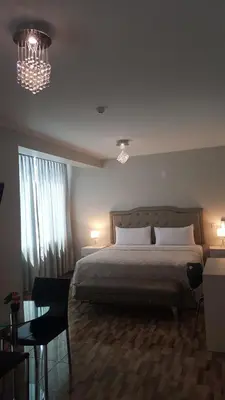 a bedroom with a large bed and a chandelier at Terraza Apart Hotel in Pichanaki