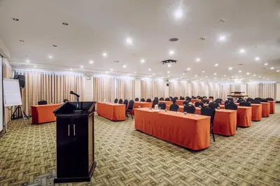 a conference room with rows of tables and a podium at Hotel Nobility in Lima