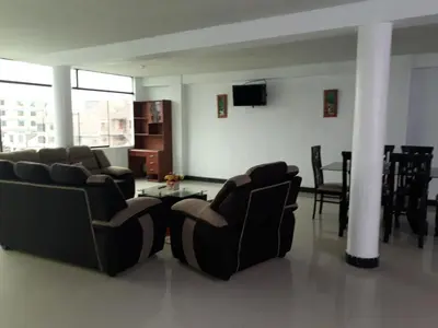 a living room with chairs and a tv and a table at B&B La Casa del Turista in Lima