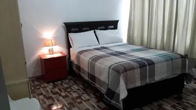 a bedroom with a bed and a lamp on a night stand at B&B La Casa del Turista in Lima
