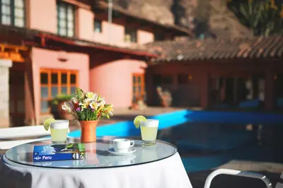 a glass table with two cups of coffee and flowers on it at Hotel San Agustin Urubamba in Urubamba