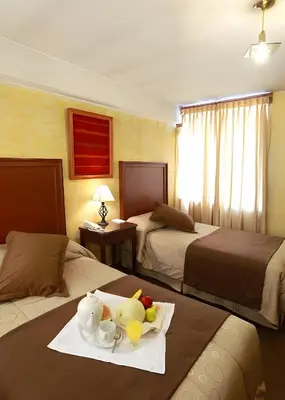 a hotel room with two beds with a tray of food at Hotel El Puma in Cusco