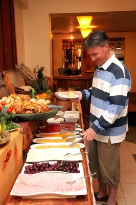 a man standing in front of a buffet of food at Hotel El Puma in Cusco