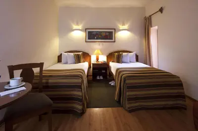 a hotel room with two beds and a table at San Agustin Internacional in Cusco