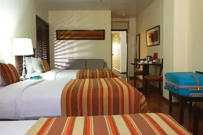 a hotel room with two beds and a table at San Agustin El Dorado in Cusco