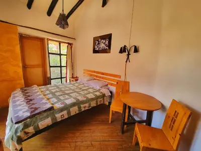 a bedroom with a bed and a table and a chair at Casa de campo Yoga Retreat in Urubamba