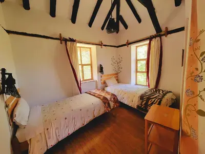 two beds in a room with two windows at Casa de campo Yoga Retreat in Urubamba
