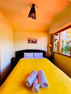 a bedroom with a yellow bed with two towels on it at La Casa de Campo in Cusco