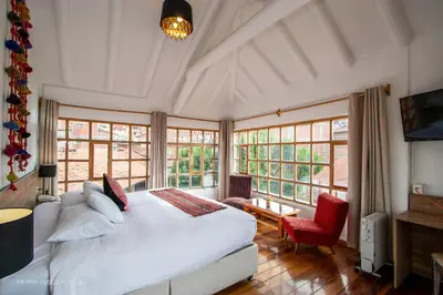 a bedroom with a large white bed and windows at Inkarri Cusco in Cusco
