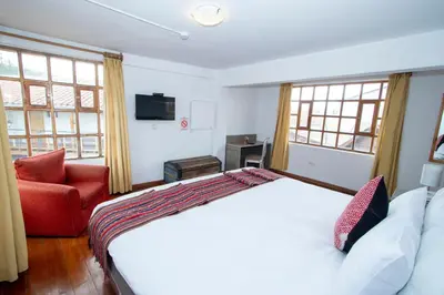 a bedroom with a white bed and a red chair at Inkarri Cusco in Cusco
