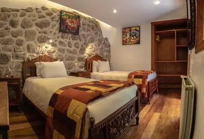 a bedroom with two beds and a stone wall at Amaru Inca in Cusco