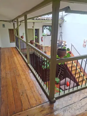 a room with a wooden floor and a balcony with potted plants at Hostal Mallqui in Cusco