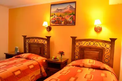 two beds in a room with orange walls at Hostal Mallqui in Cusco