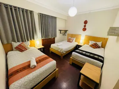 a hotel room with two beds and two tables at TATA Hotel Boutique in Cusco