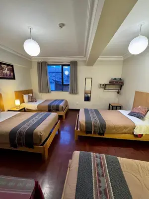 a hotel room with three beds and two windows at TATA Hotel Boutique in Cusco