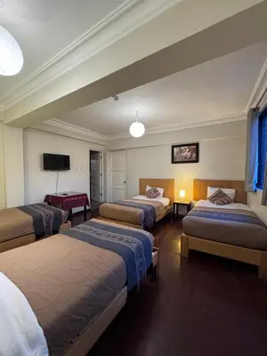 a hotel room with three beds and a tv at TATA Hotel Boutique in Cusco