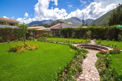 a garden with flowers and a stone path at Hotel Agustos Urubamba in Urubamba