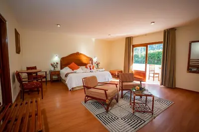 a bedroom with a bed and a table and chairs at Hotel Agustos Urubamba in Urubamba