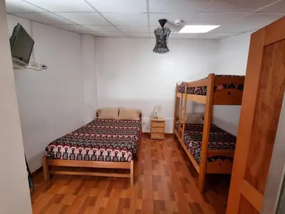 a bedroom with two bunk beds and a flat screen tv at Chelitos Backpacker in Cusco