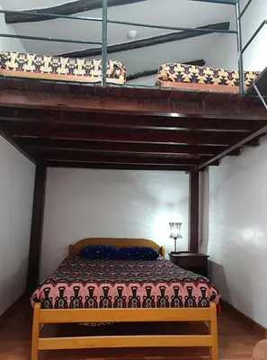 two loft beds in a room with a bed underneath at Chelitos Backpacker in Cusco