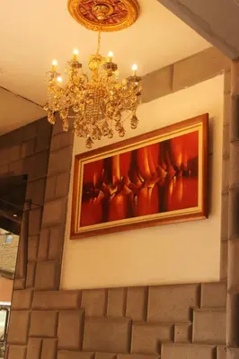 a painting hanging on a wall with a chandelier at Tinoco Apart Hotel in Ayacucho