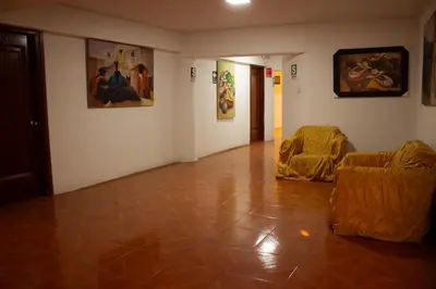 a room with two chairs and paintings on the walls at Tinoco Apart Hotel in Ayacucho