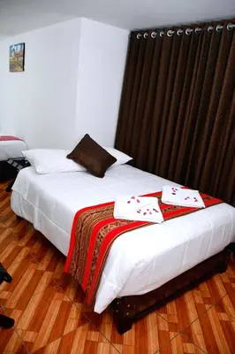 a bedroom with two beds with white sheets and a window at Peru Coca B&B Machupicchu in Machu Picchu