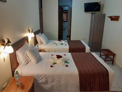 two beds in a hotel room with flowers on them at Margarita's House Machupicchu in Machu Picchu