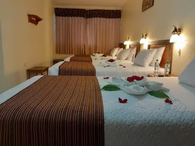 two beds in a hotel room with flowers on them at Margarita's House Machupicchu in Machu Picchu